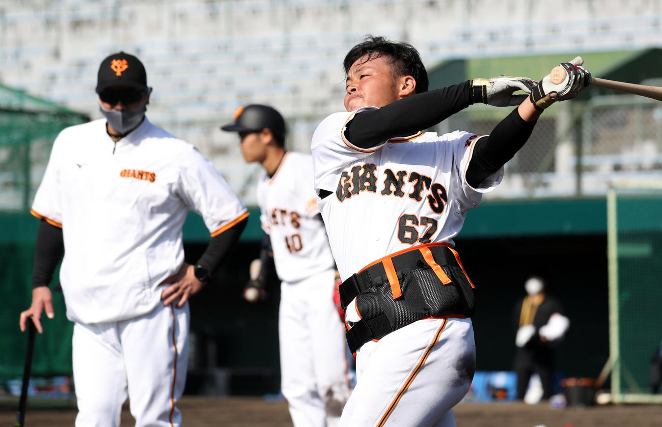 阿部2軍監督（後方）が見つめる中、腰に重りを着けて、ロングティーを放つ山瀬（撮影・狩俣裕三）
