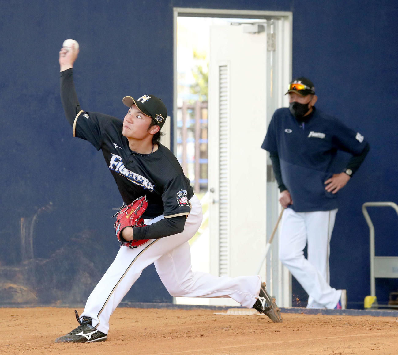 ブルペンで投球する日本ハム伊藤。右奥は荒木投手コーチ（撮影・佐藤翔太）