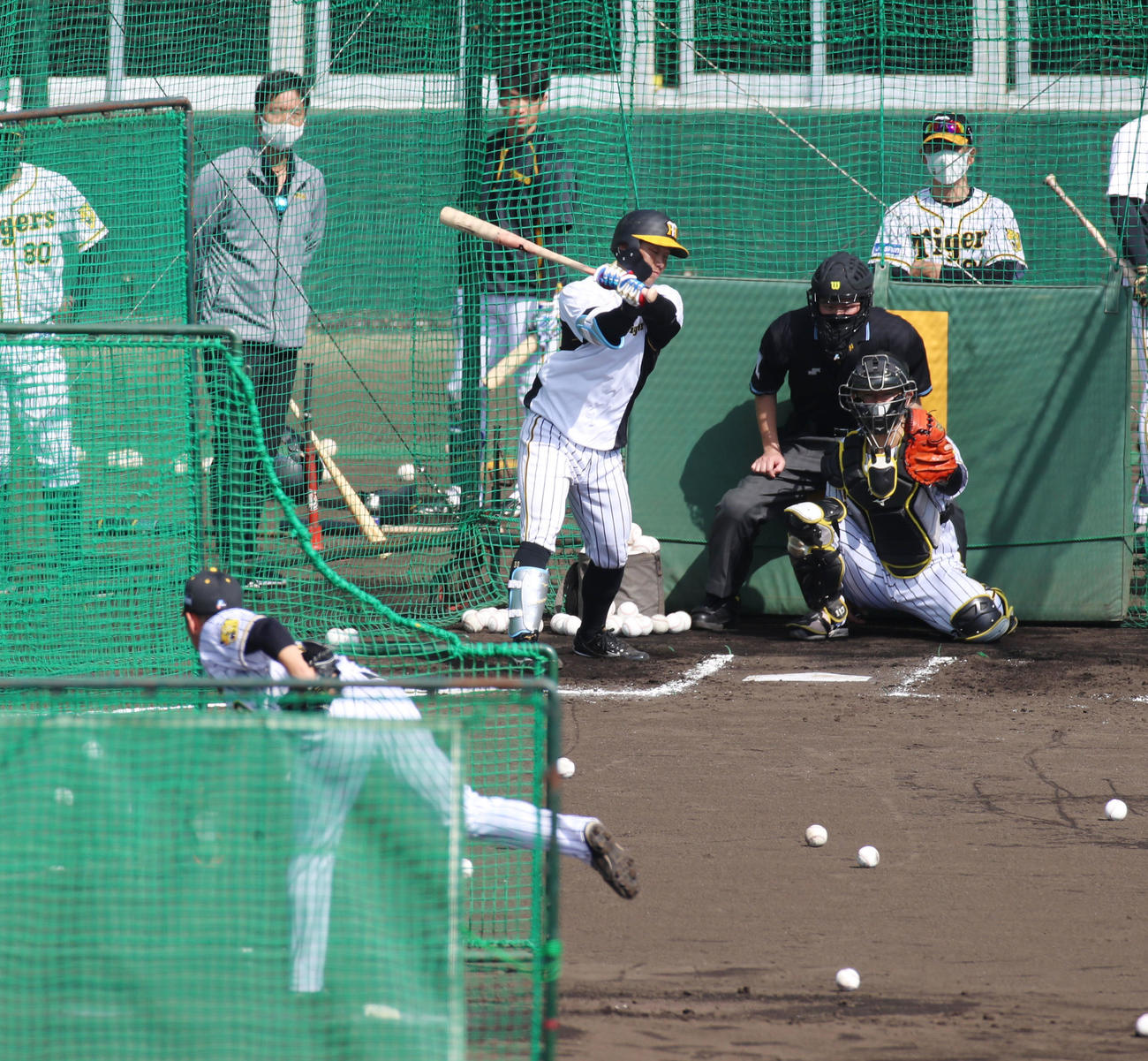 打撃投手を務めた阪神石井大智は糸原から空振りを奪う。右は矢野監督、左は藤川SA（撮影・加藤哉）