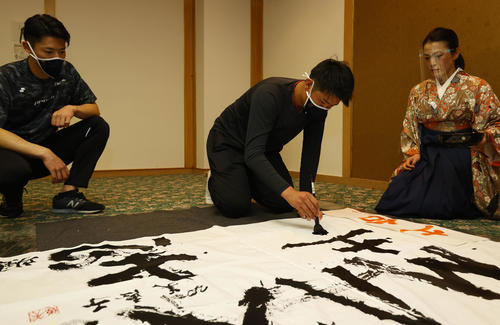 キャンプ休日に書道で今年の目標を書にしたためる中川颯（左）と山下。右は今井美恵子講師