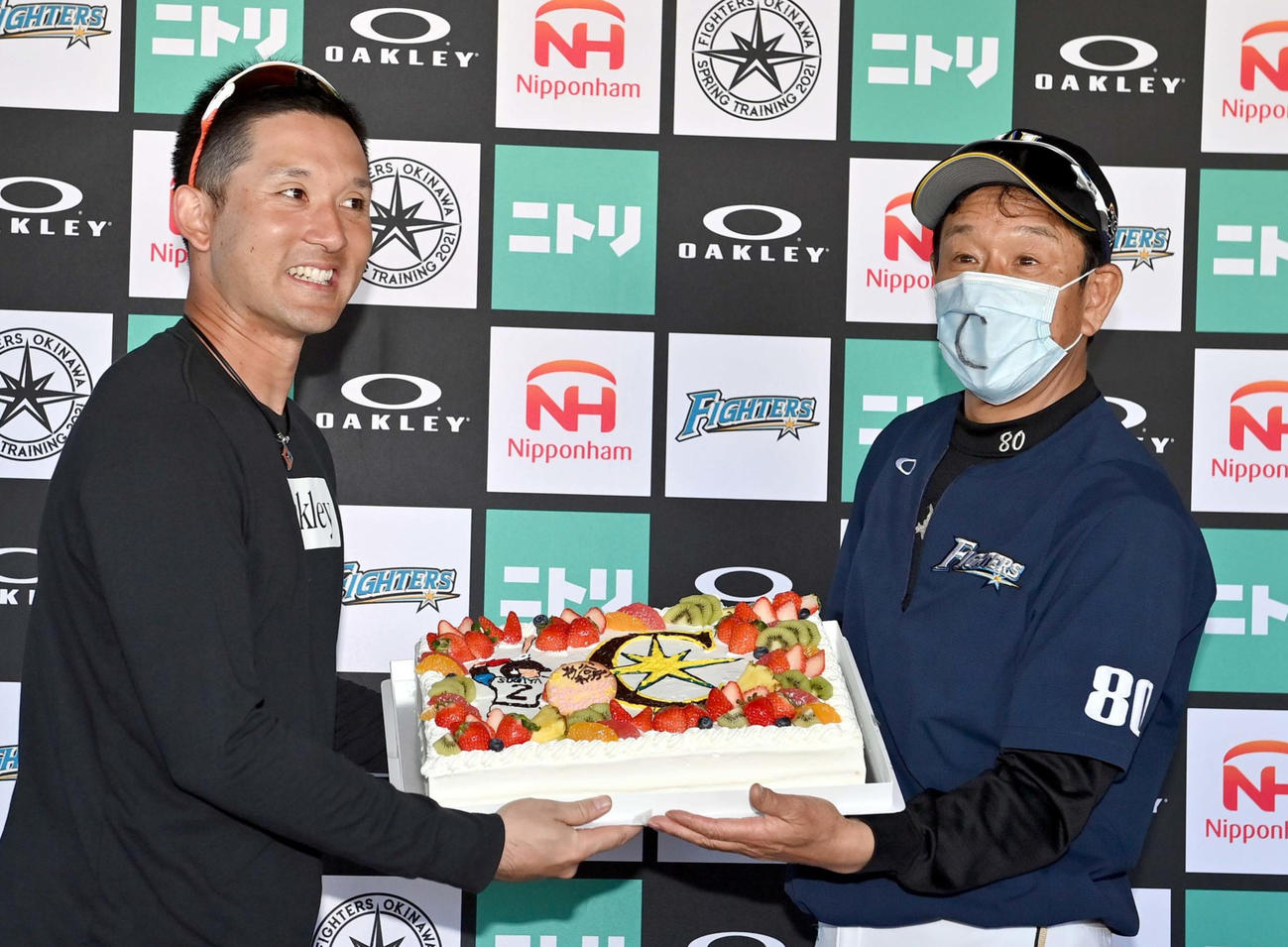 直筆で「C」と書かれたマスクを付けた栗山監督（右）と笑顔で写真に納まる日本ハム杉谷（代表撮影）