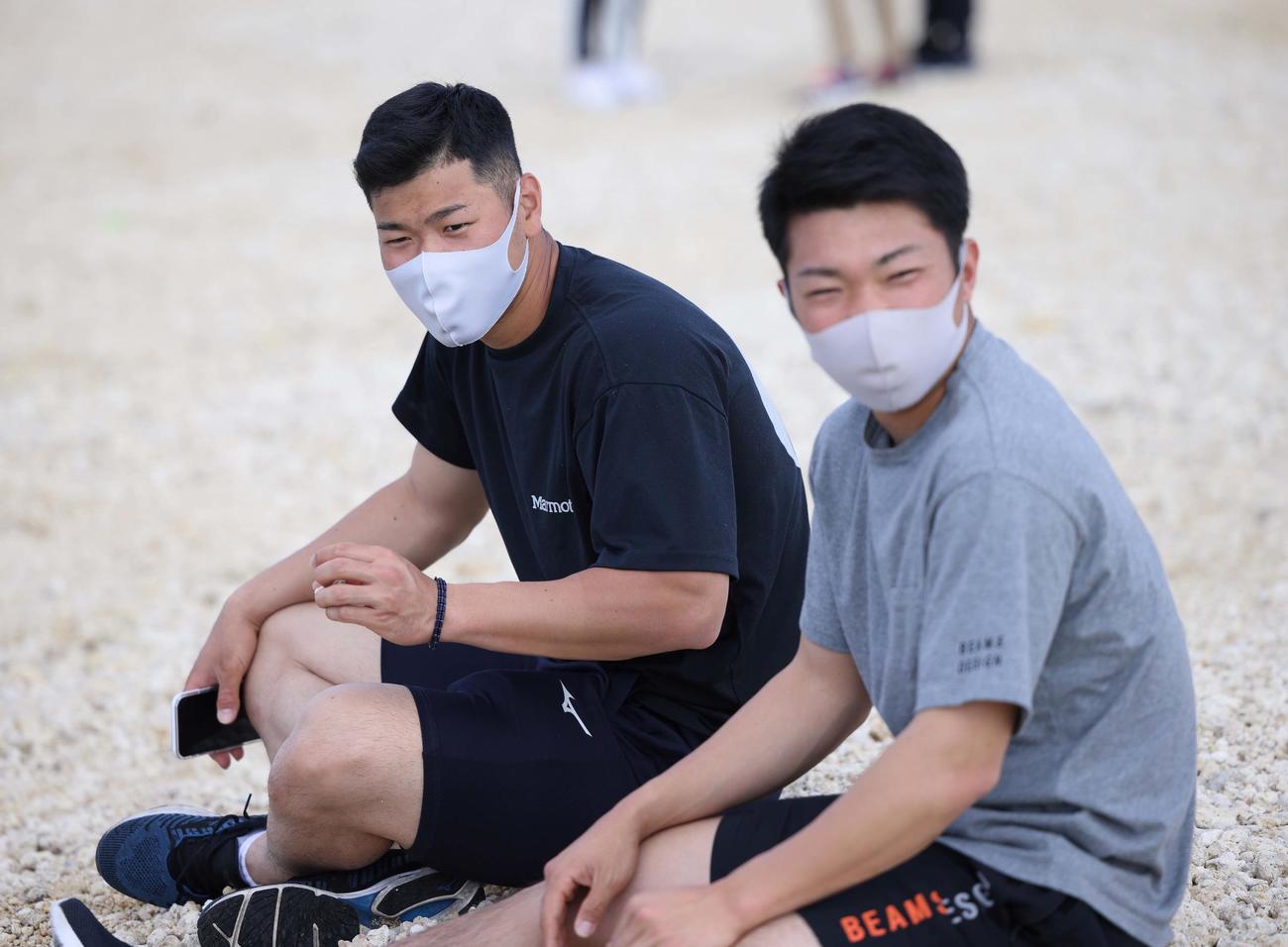 休日に沖縄の海を満喫する佐藤輝（左）と石井大（球団提供）