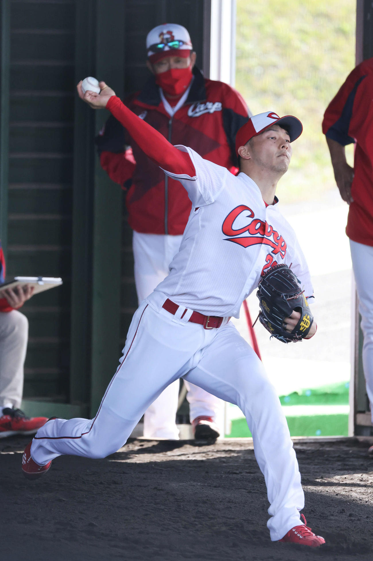 プロ野球広島沖縄キャンプ　ブルペンで投げる薮田。後ろは佐々岡監督（撮影・加藤孝規）