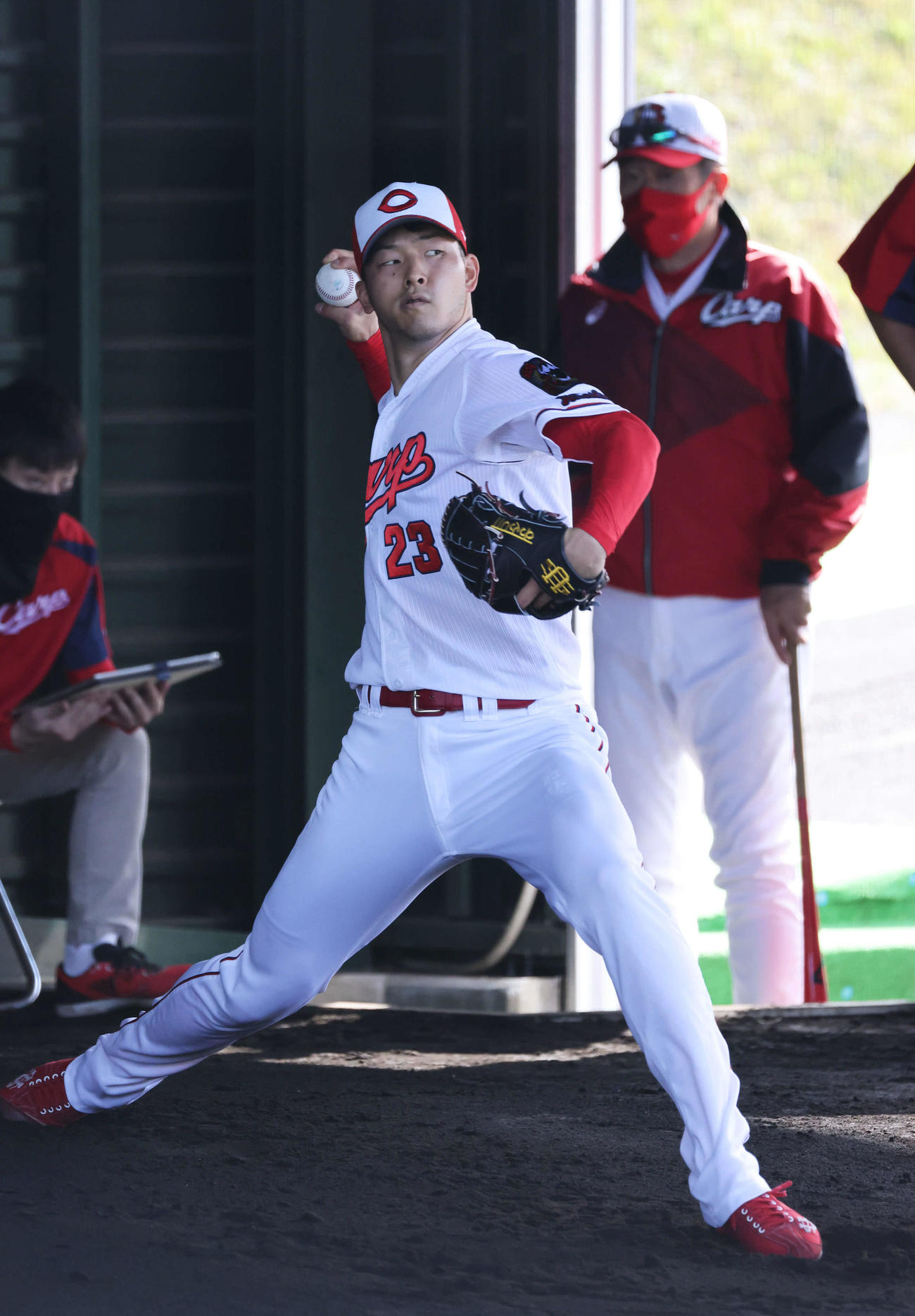 プロ野球広島沖縄キャンプ　ブルペンで投げる薮田。右は佐々岡監督（撮影・加藤孝規）