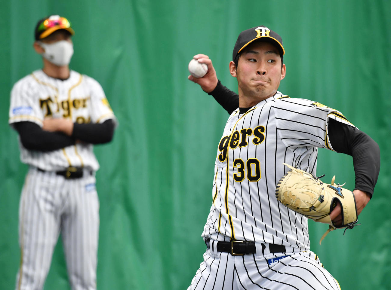 ブルペンで投球する阪神佐藤蓮。左は見つめる矢野監督（代表撮影）