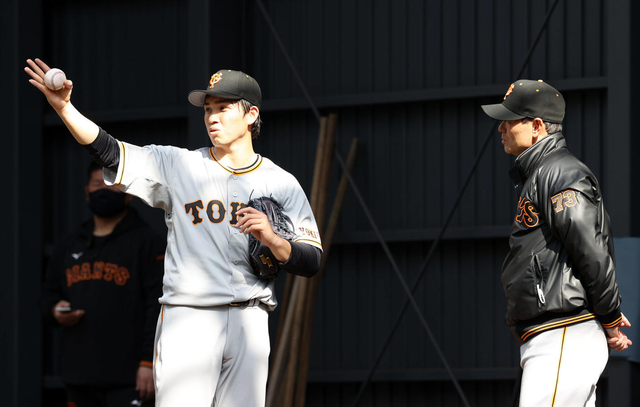 桑田投手チーフコーチ補佐（右）とブルペンで話し合う高橋（撮影・狩俣裕三）