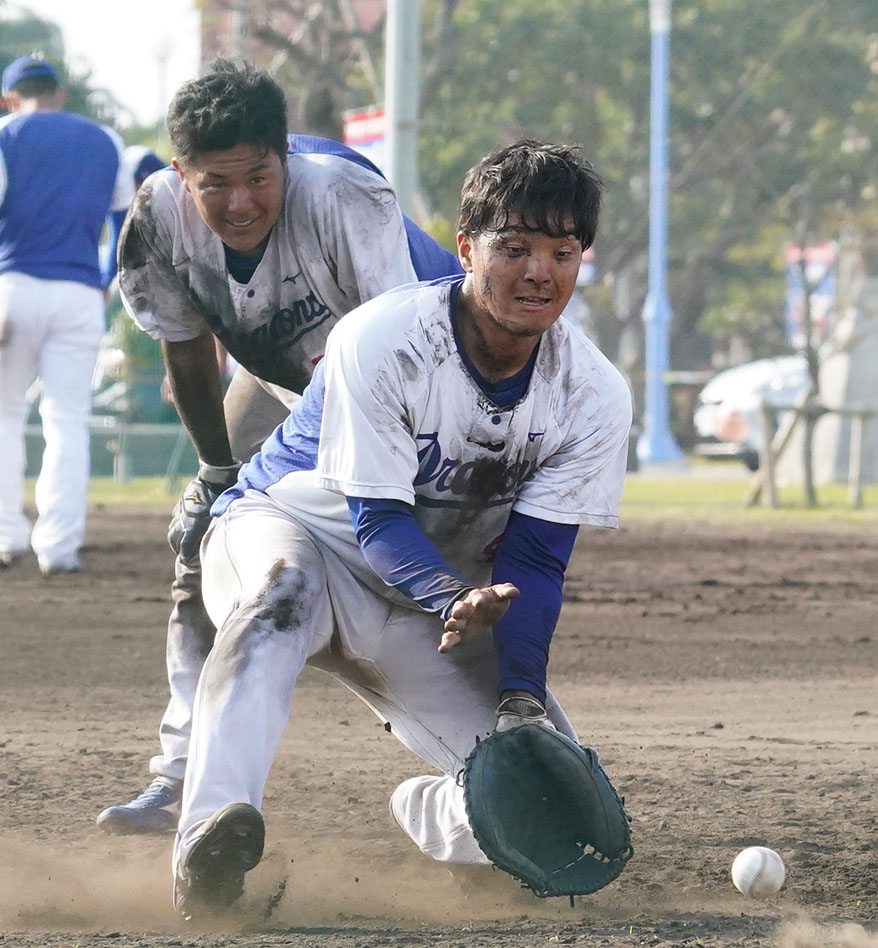 泥まみれになりながらノックを受ける郡司裕也（奥は木下拓哉）（撮影・森本幸一）＝2021年2月8日、沖縄県北谷町のAgreスタジアム北谷