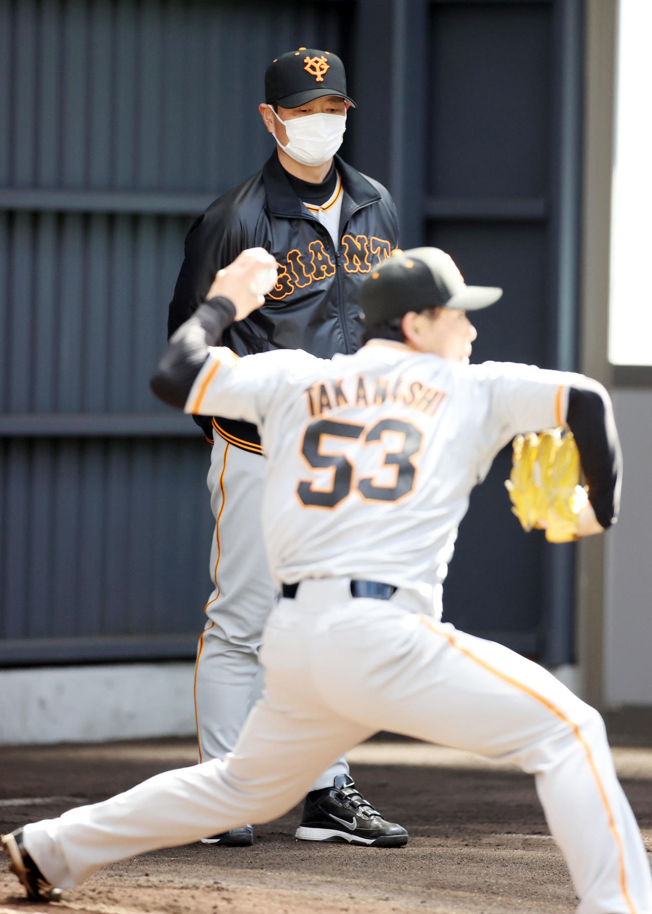 ブルペンで投げ込む高梨（手前）をじっと見つめる桑田投手チーフコーチ補佐（撮影・狩俣裕三）