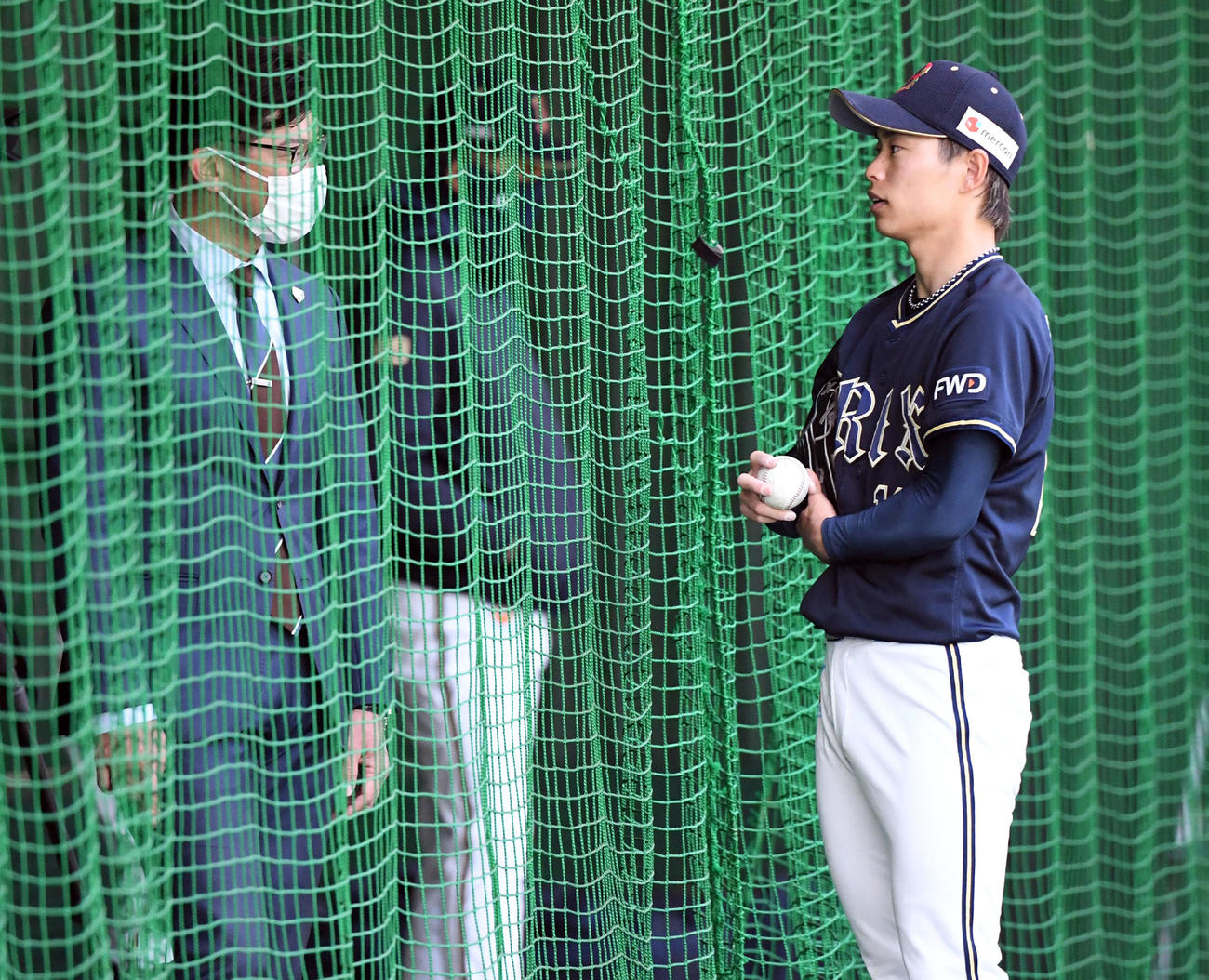 ブルペンで投球練習を終えたオリックス山岡（右）は侍JAPAN建山コーチと話す（撮影・前岡正明）