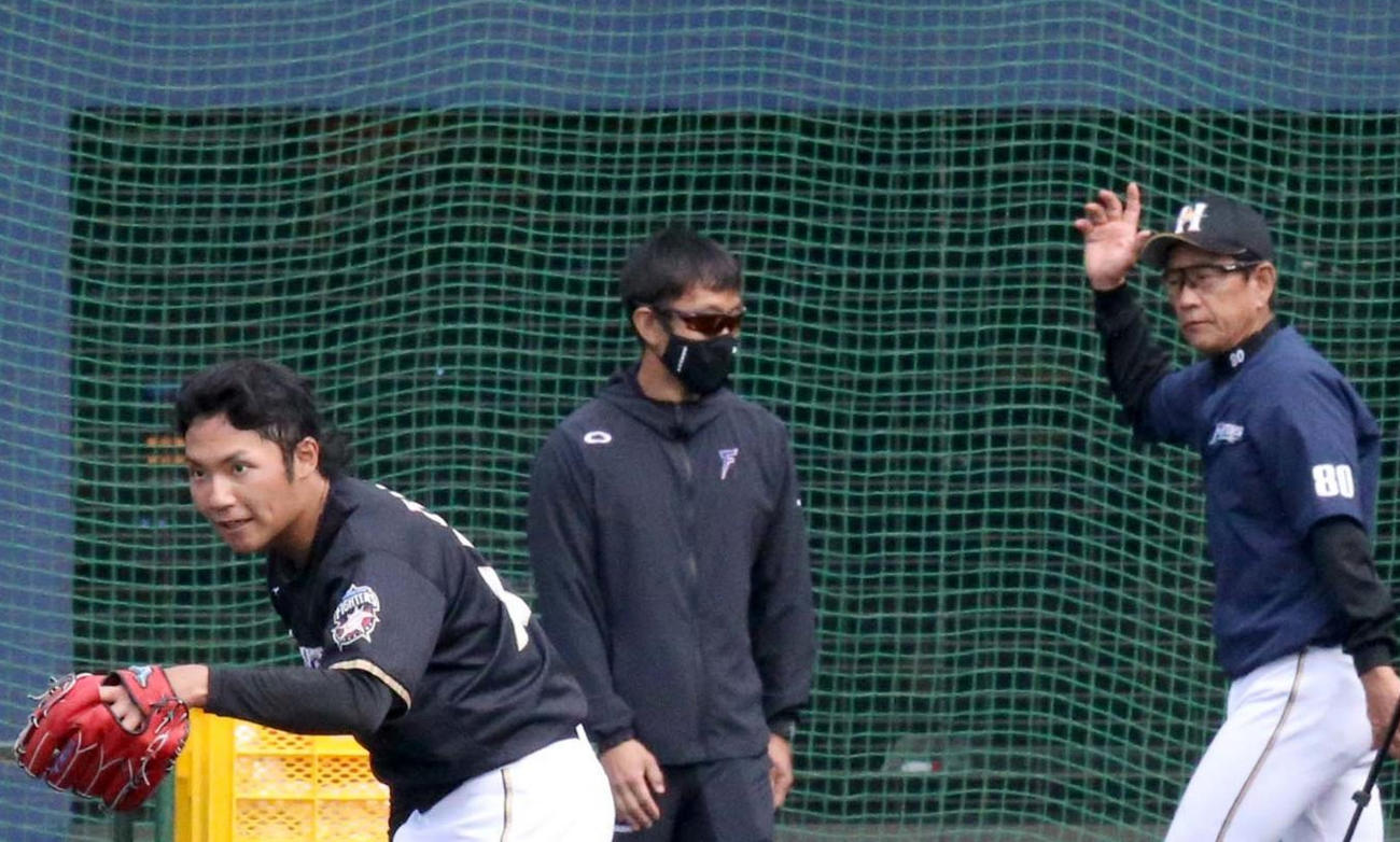 お辞儀をしながら引き揚げる日本ハム伊藤（左手前）とそれを見届け練習試合へ向かう栗山監督（右）（撮影・佐藤翔太）