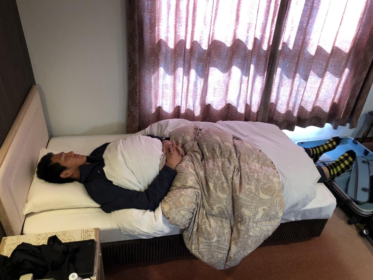 宿舎のベッドに寝る秋広（球団提供）
