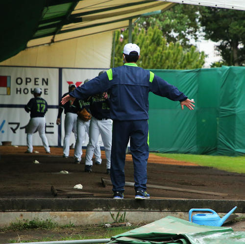 強風の影響でブルペンのパーテーションが倒れ、両手を広げ壁になる古田臨時コーチ（撮影・河田真司）