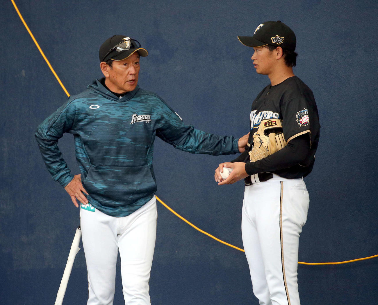 ブルペンで鈴木健（右）と話す日本ハム栗山監督（撮影・黒川智章）　　　