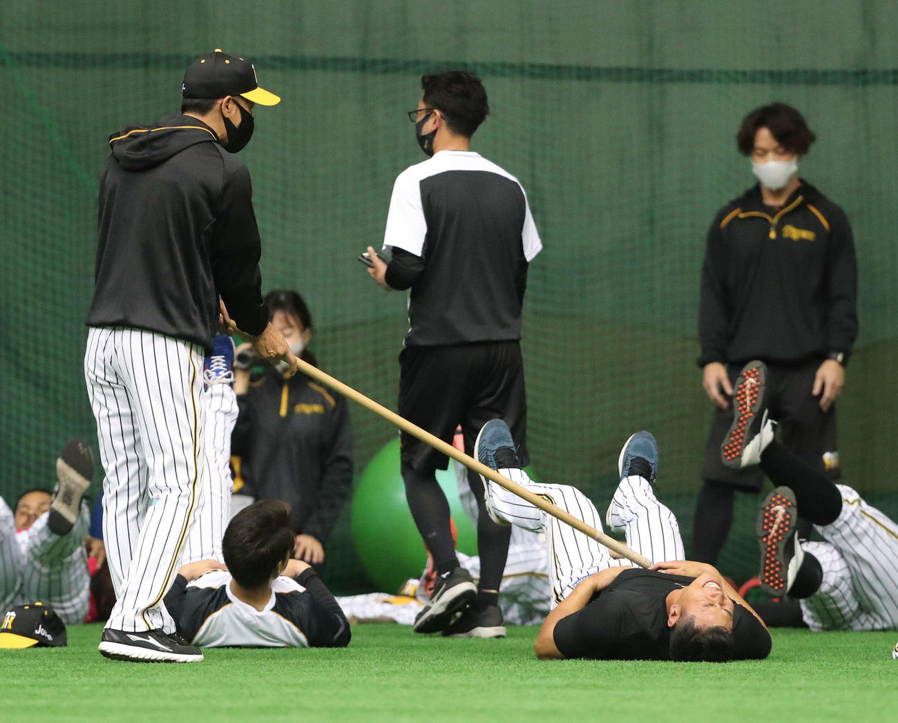 腹筋運動をする佐藤輝明を棒でつっつく矢野燿大監督