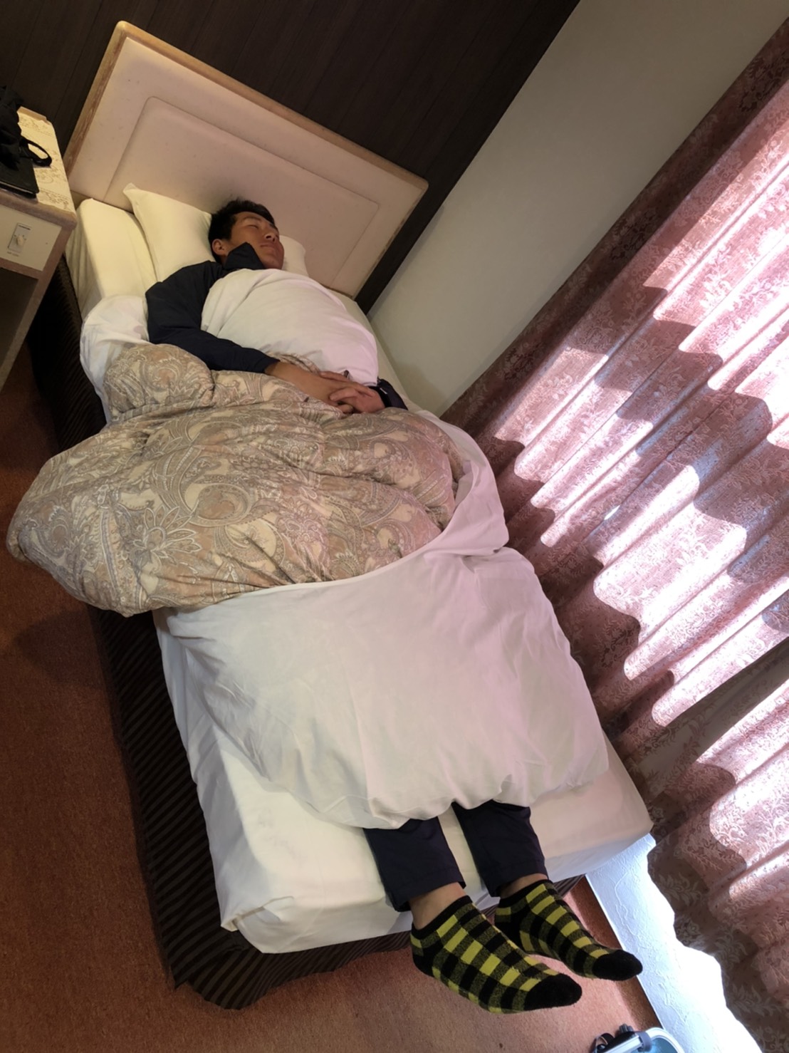 宿舎のベッドに寝る秋広（球団提供）