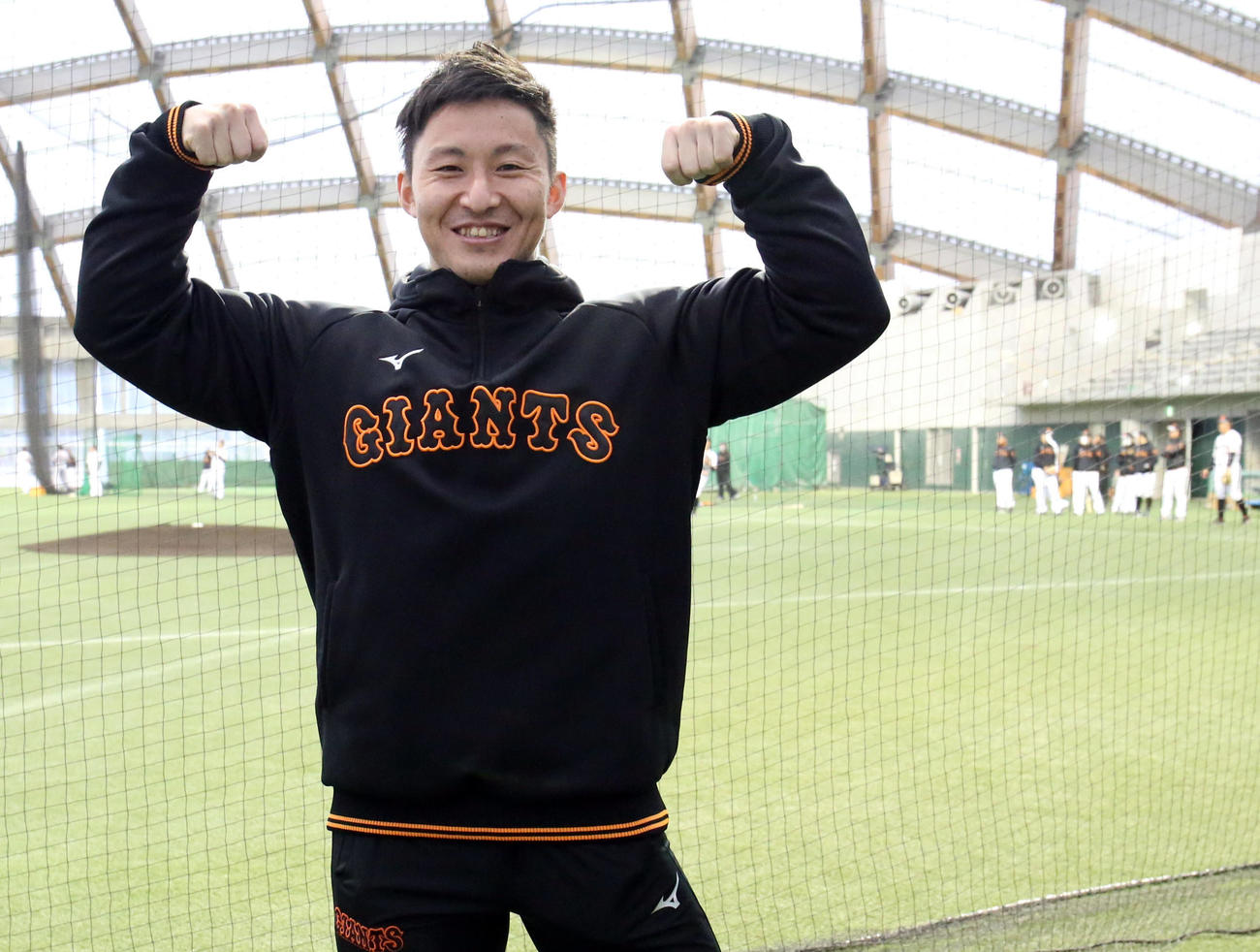 日本選手権9連覇の実績を誇るボディービルダー鈴木氏が球団スタッフとして招かれた。巨人の選手たちが練習する中、得意ポーズを決める（撮影・狩俣裕三）