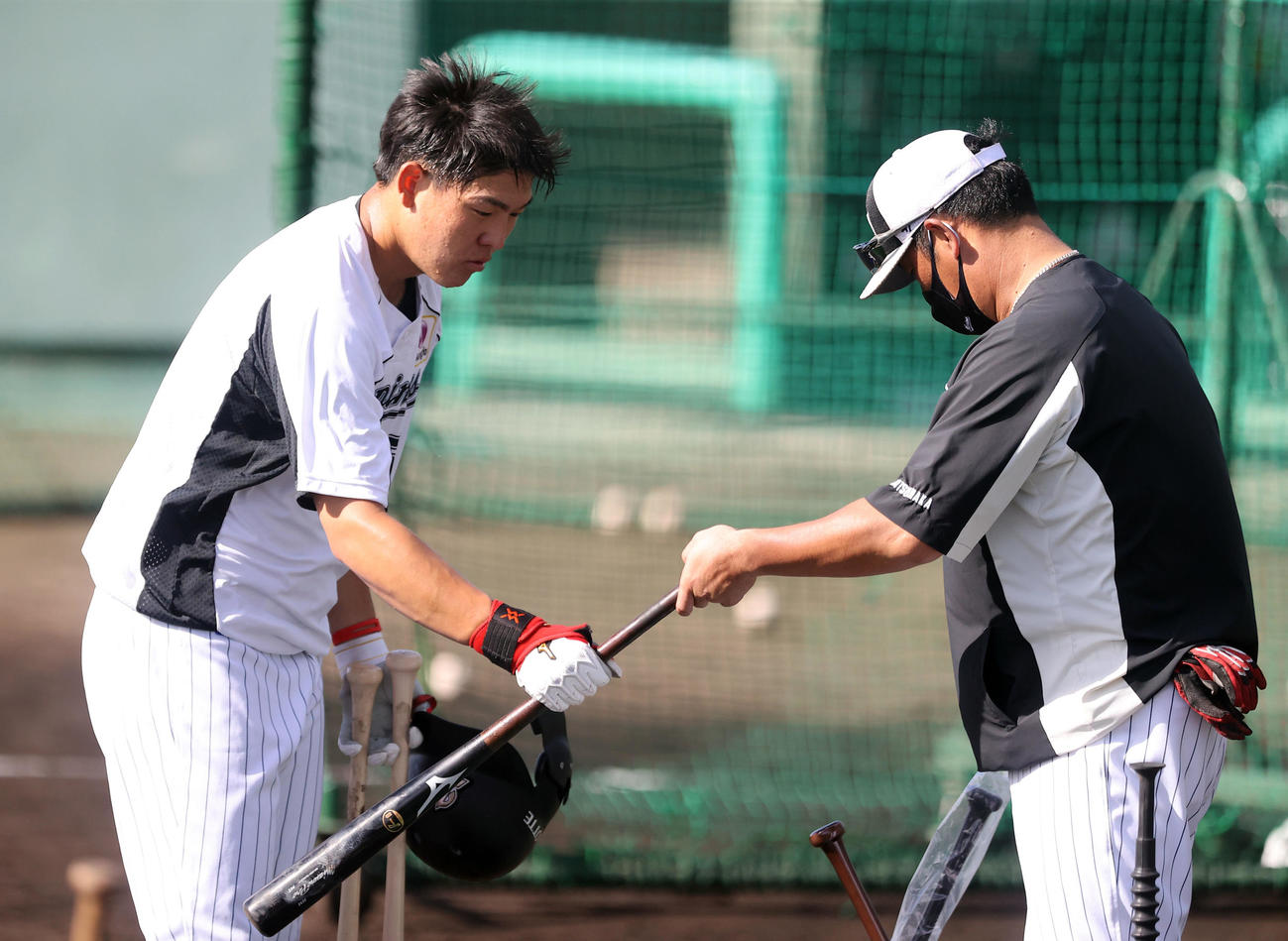 打撃練習の合間に松中臨時コーチ（右）からバットを渡されるロッテ安田（撮影・垰建太）