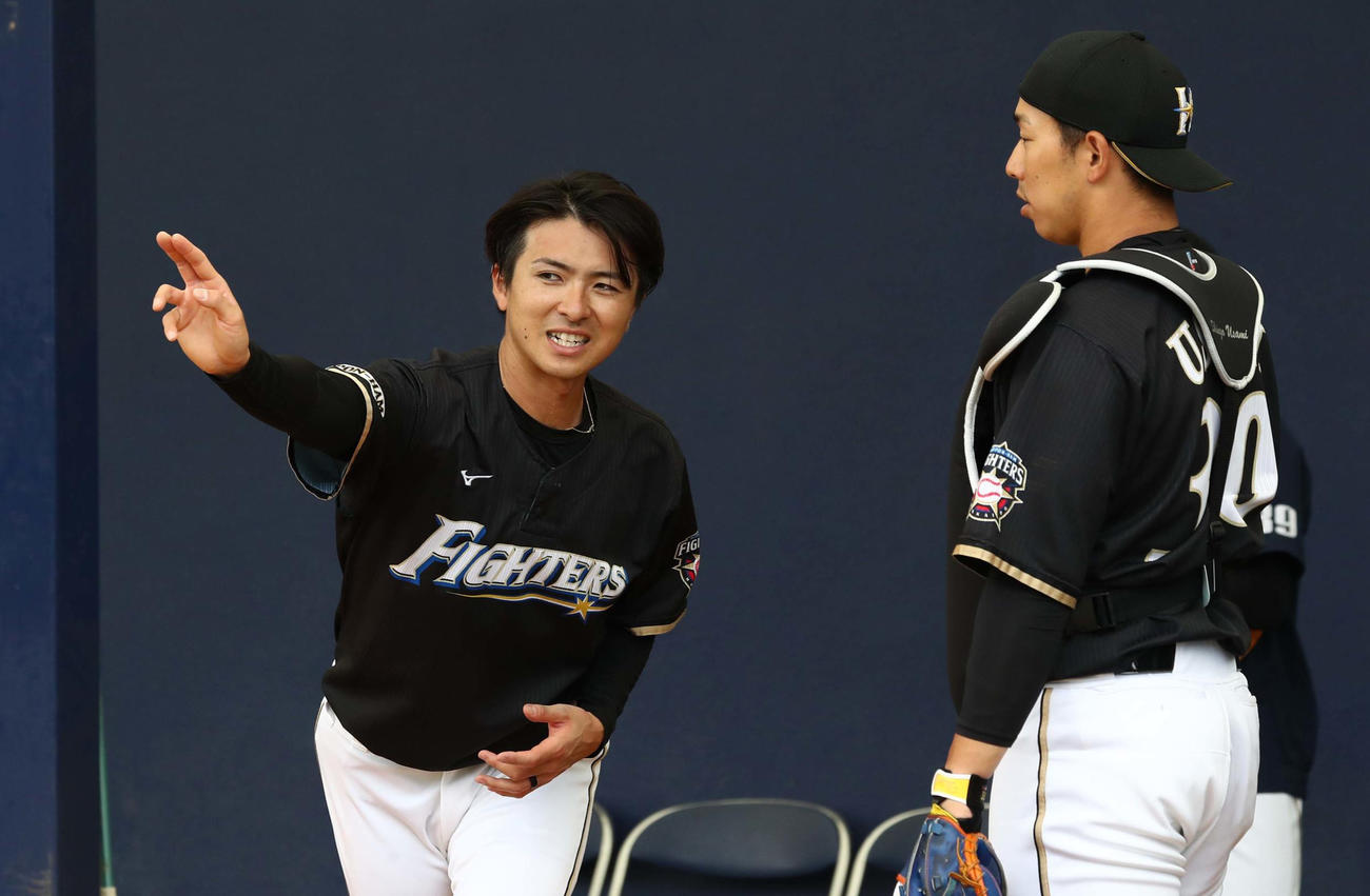 ブルペンで投球後、宇佐見（右）と話す上沢（撮影・黒川智章）　　