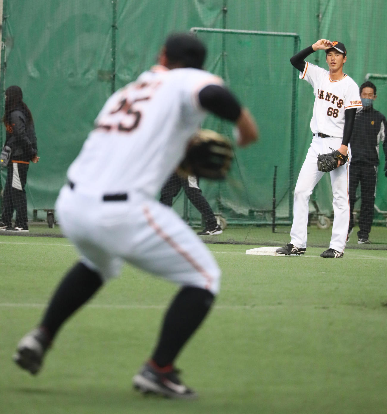 一塁守備練習を行う巨人秋広。手前は岡本和（撮影・足立雅史）