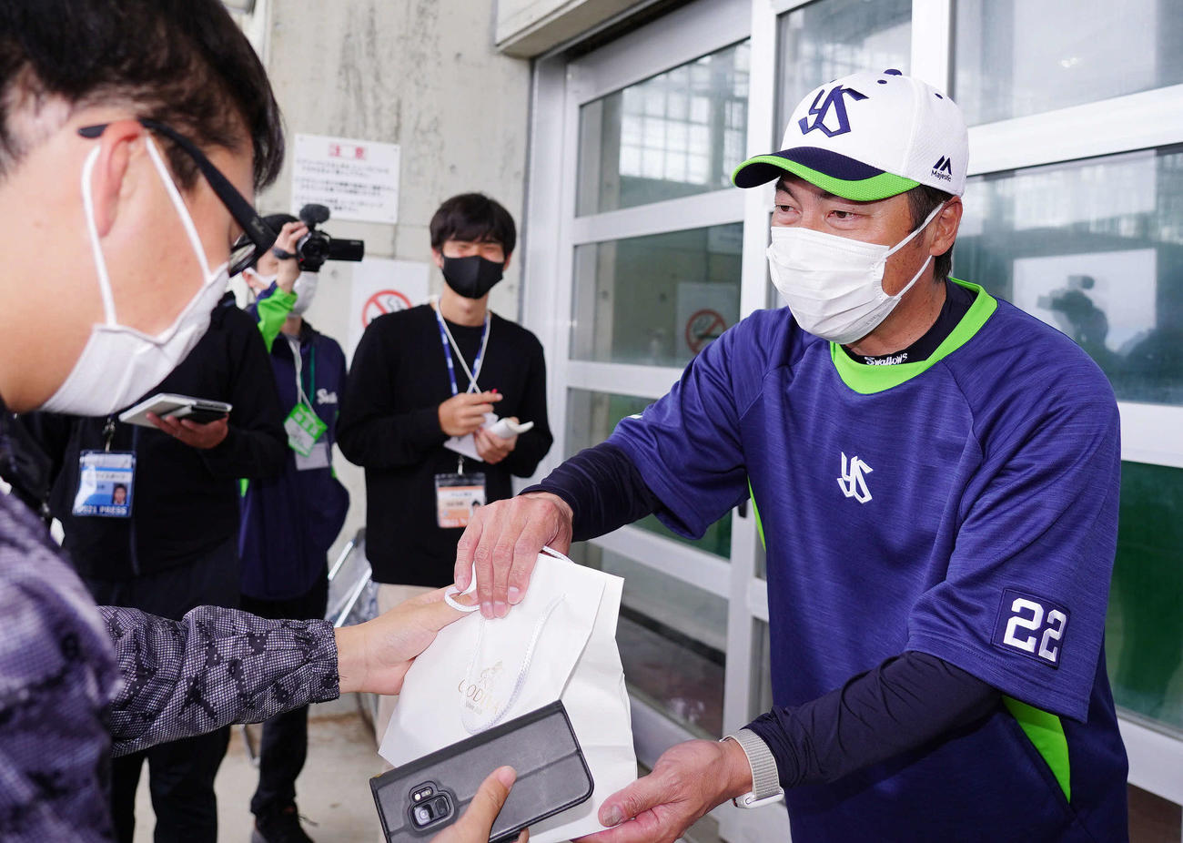 男性記者からバレンタインチョコレートをもらうヤクルト高津監督（球団提供）