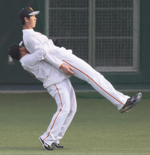練習中、身長2mの巨人秋広は戸根（174cm）に持ち上げられる（撮影・足立雅史）
