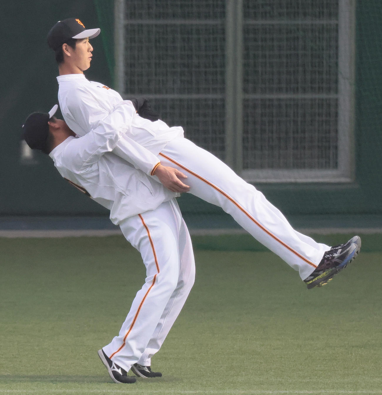 練習中、巨人秋広は戸根に持ち上げられる（撮影・足立雅史）