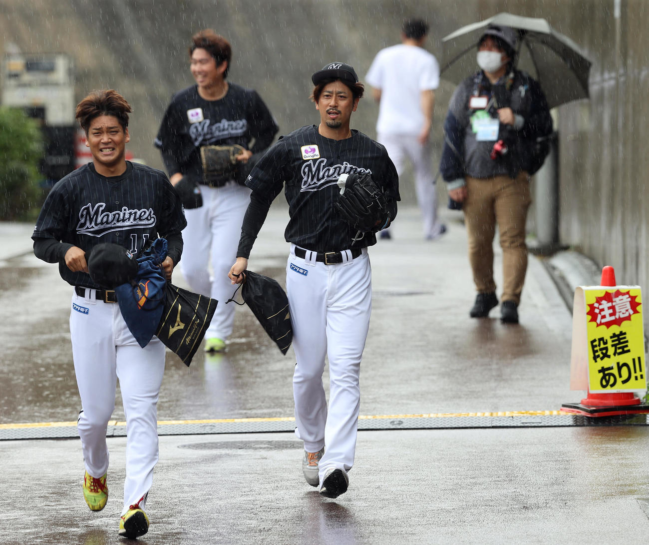 ヤクルト対ロッテ　練習試合が雨天中止となりロッテ先発予定だった大嶺（中央）は小走りで室内練習場に移動する（撮影・垰建太）