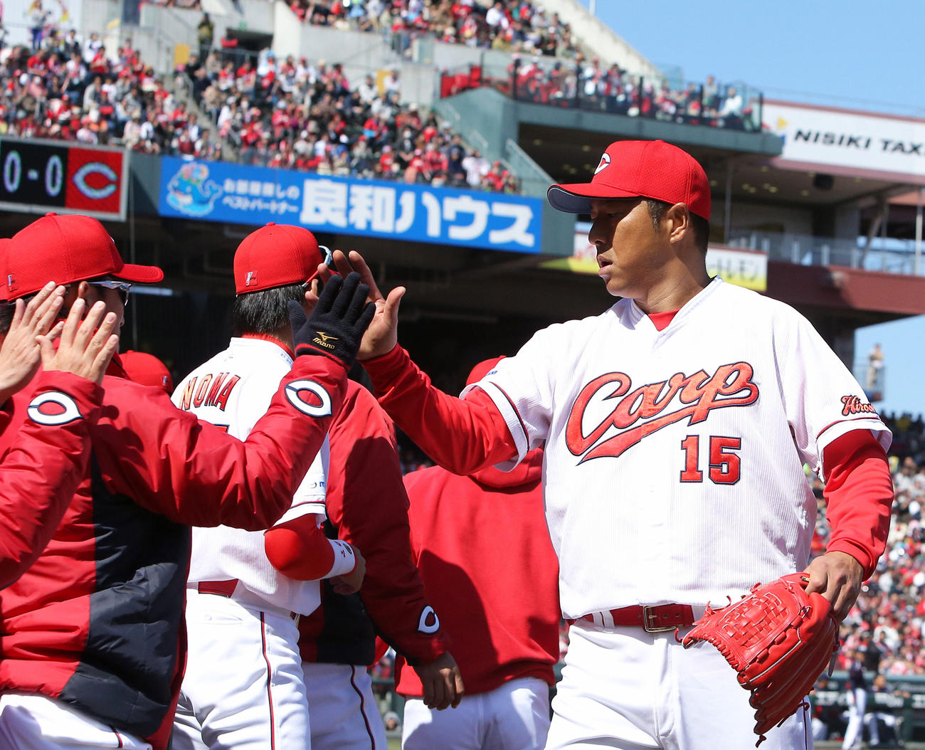 日本復帰後の初登板を、無安打無失点で終えた広島黒田はナインとタッチをかわす（2015年3月8日撮影）