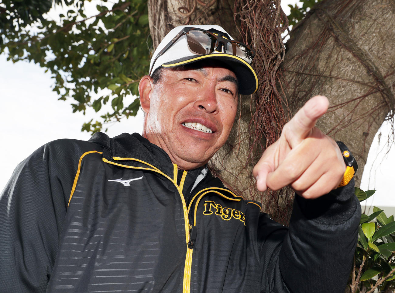 宜野座のガジュマルの木の前でポーズを決める井上ヘッドコーチ（撮影・前田充）