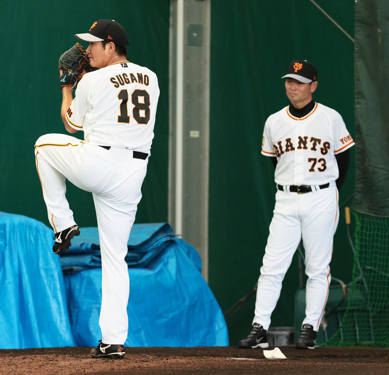 巨人桑田投手チーフコーチ補佐（右）が見つめる中、ブルペン投球する菅野（撮影・足立雅史）