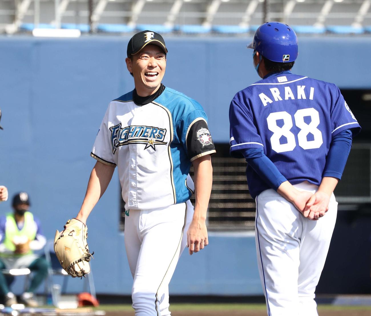 日本ハム対中日　6回に登板し打者を3人で抑えた宮西（左）は中日荒木コーチに声をかけられ笑顔を見せる（撮影・黒川智章）