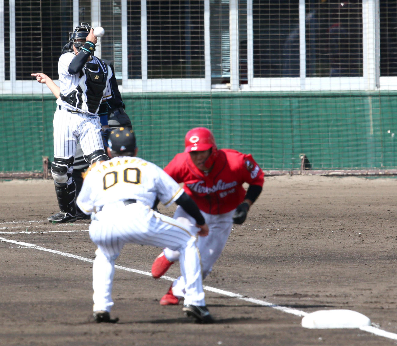 阪神対広島・練習試合　3回表広島1死三塁、梅野隆太郎（上）は三走石原貴規（右）を三塁けん制で刺す、手前左は山本泰寛（撮影・上山淳一）