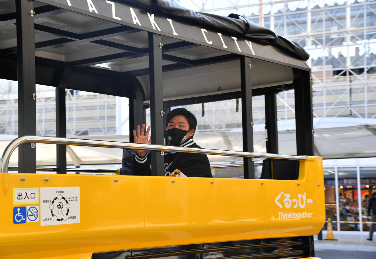 キャンプ休日の新人体験で、小型低速電動バス「ぐるっぴー」に乗車し宮崎駅前を出発する井上（撮影・岩下翔太）