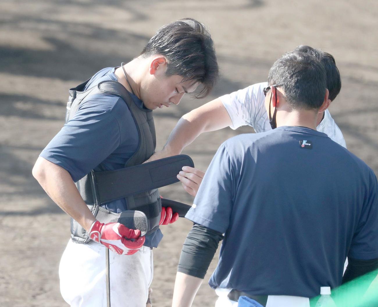 2人がかりで重量10キロのウエイトジャケットを付けてもらう日本ハム野村（撮影・黒川智章）