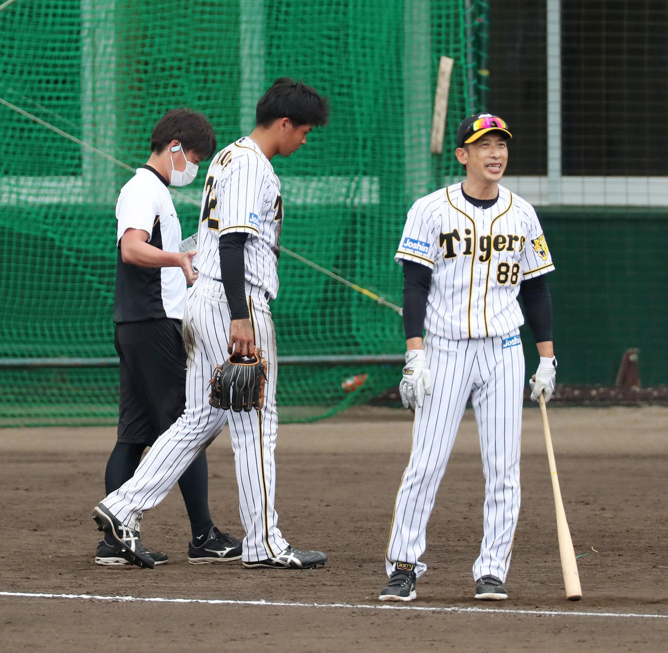 デスノック最中に足を負傷し、引きずりながら歩く井上、右はノックを打つ矢野監督（撮影・加藤哉）