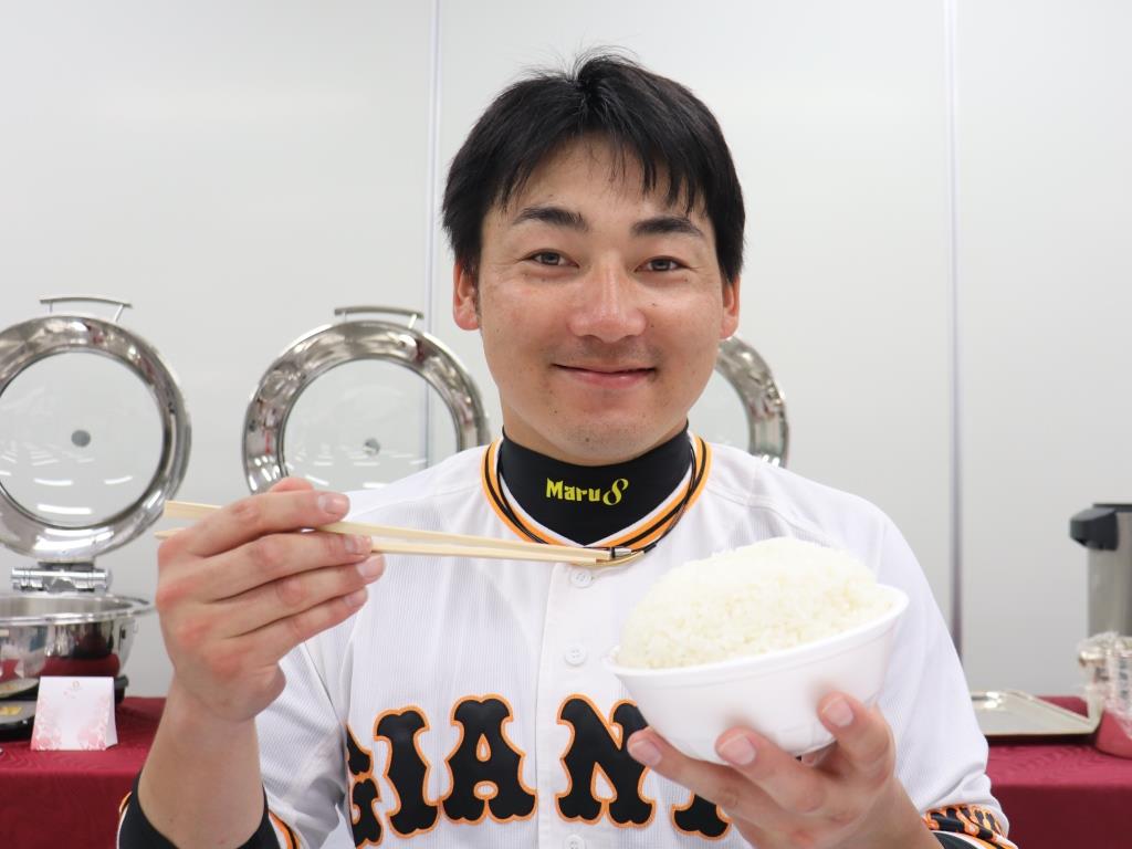 大盛りご飯を持ち、笑顔を見せる巨人丸（球団提供）
