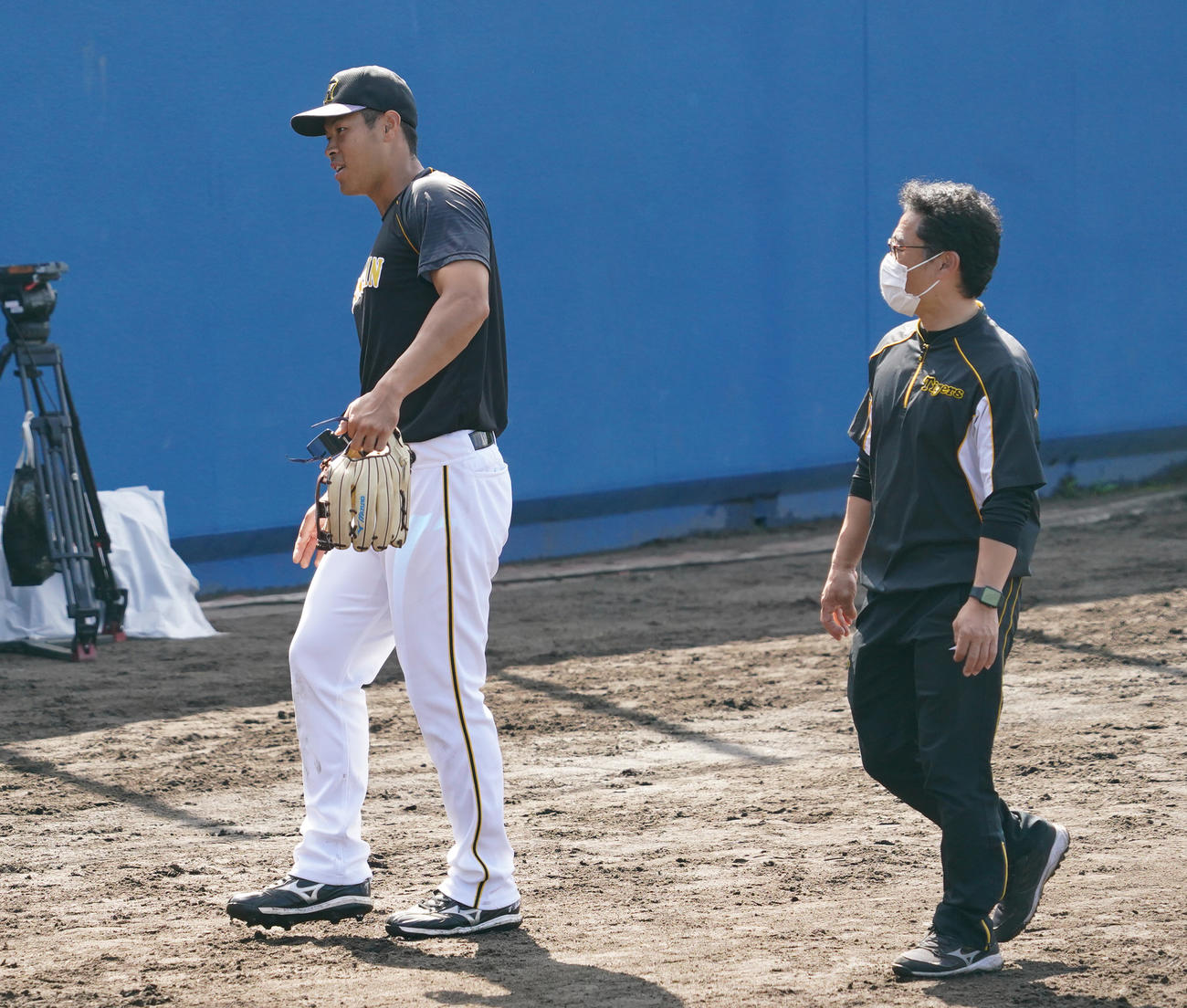 試合前の外野守備練習で佐藤輝明は足を滑らせトレーナーとともにベンチに戻る（撮影・清水貴仁）