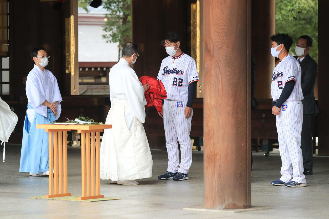 明治神宮を参拝し、宮司の中島精太郎さんから赤色のジャンパーを受け取るヤクルト高津監督（中央）