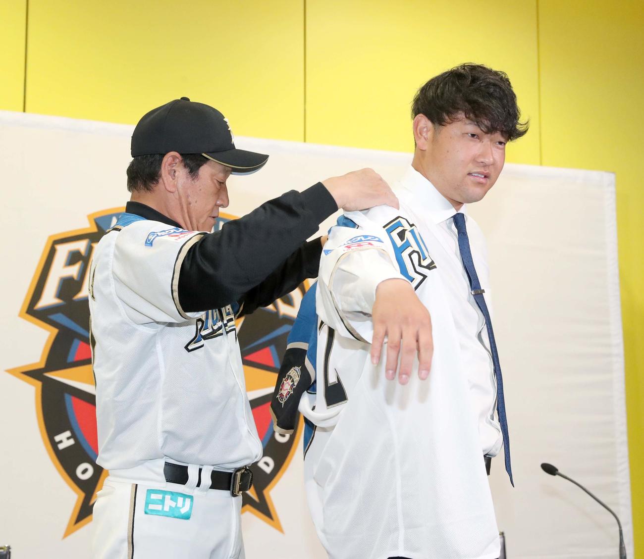 日本ハム栗山監督（左）にユニホームを着せてもらう池田（撮影・佐藤翔太）