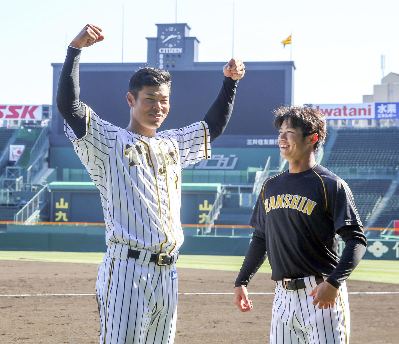 佐藤輝は甲子園球場のスコアボードをバックにポーズを決める、右は中野（撮影・上山淳一）