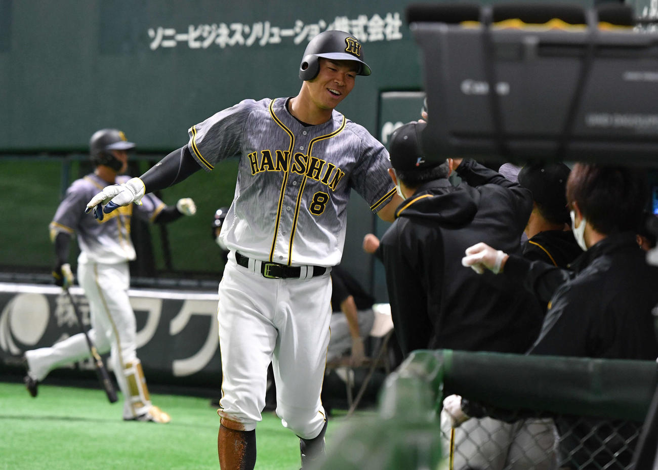 ソフトバンク対阪神　9回表阪神無死満塁、高山（左奥）の中犠飛で生還し、ナインの出迎えに笑顔を見せる佐藤輝（撮影・岩下翔太）