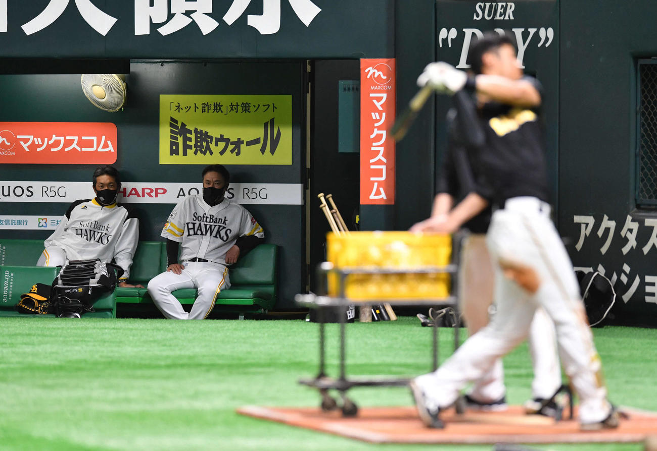 ティー打撃を行う阪神・佐藤輝（右）をベンチから見つめるソフトバンク・小久保ヘッドコーチ（後方左）と村松コーチ（撮影・岩下翔太）