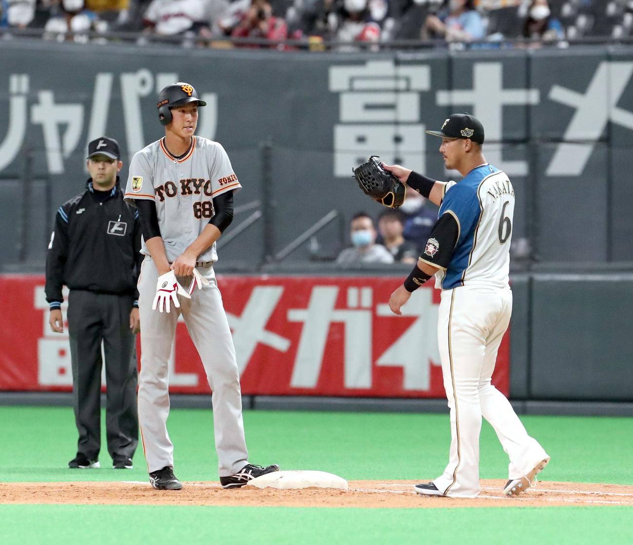 3月6日の日本ハム戦の5回表に、巨人秋広は右前打を放ち日本ハム一塁手の中田と言葉を交わす（撮影・佐藤翔太）