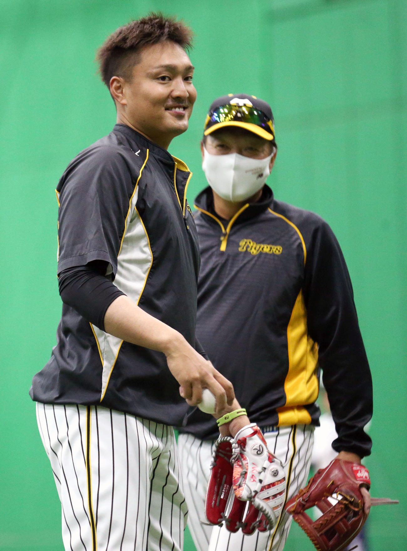 秋山拓巳はリラックスした表情でキャッチボールする、右は福原忍投手コーチ（2021年3月7日撮影）