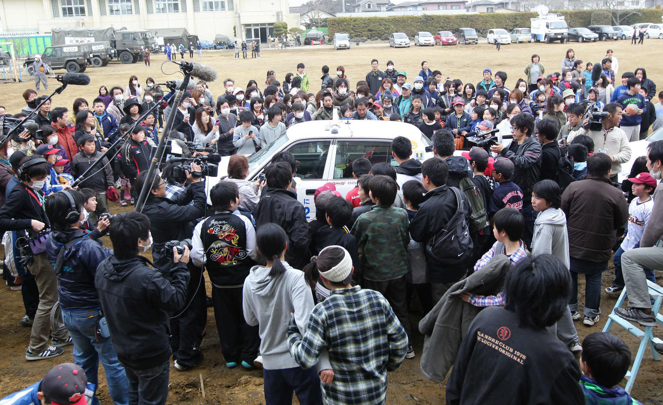 11年4月、東松島市立大曲小学校を訪れた楽天田中将が乗るタクシーを多くの人が囲む