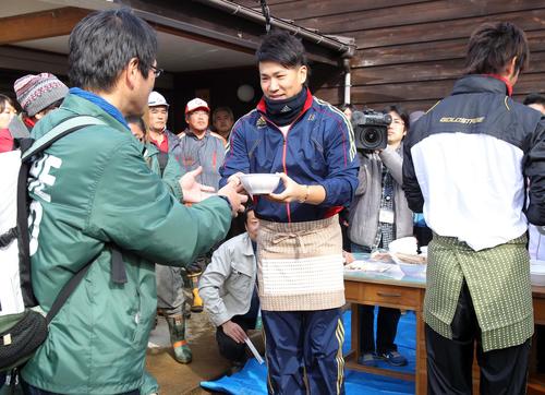 12年12月　福島市内の除染作業ボランティアへの炊き出しで、エプロン姿で作業ボランティアにうどんを手渡す