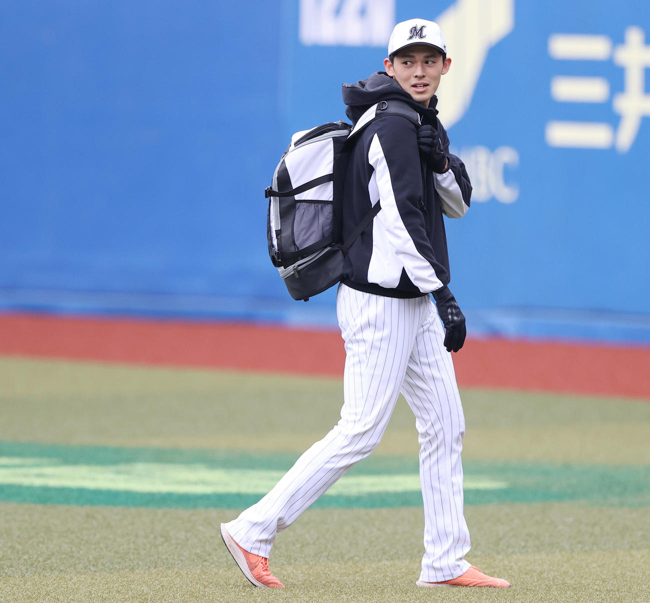 ロッテ対中日　試合前練習を終えチームメートから声をかけられ笑顔を見せながら引き揚げるロッテ佐々木朗（撮影・垰建太）