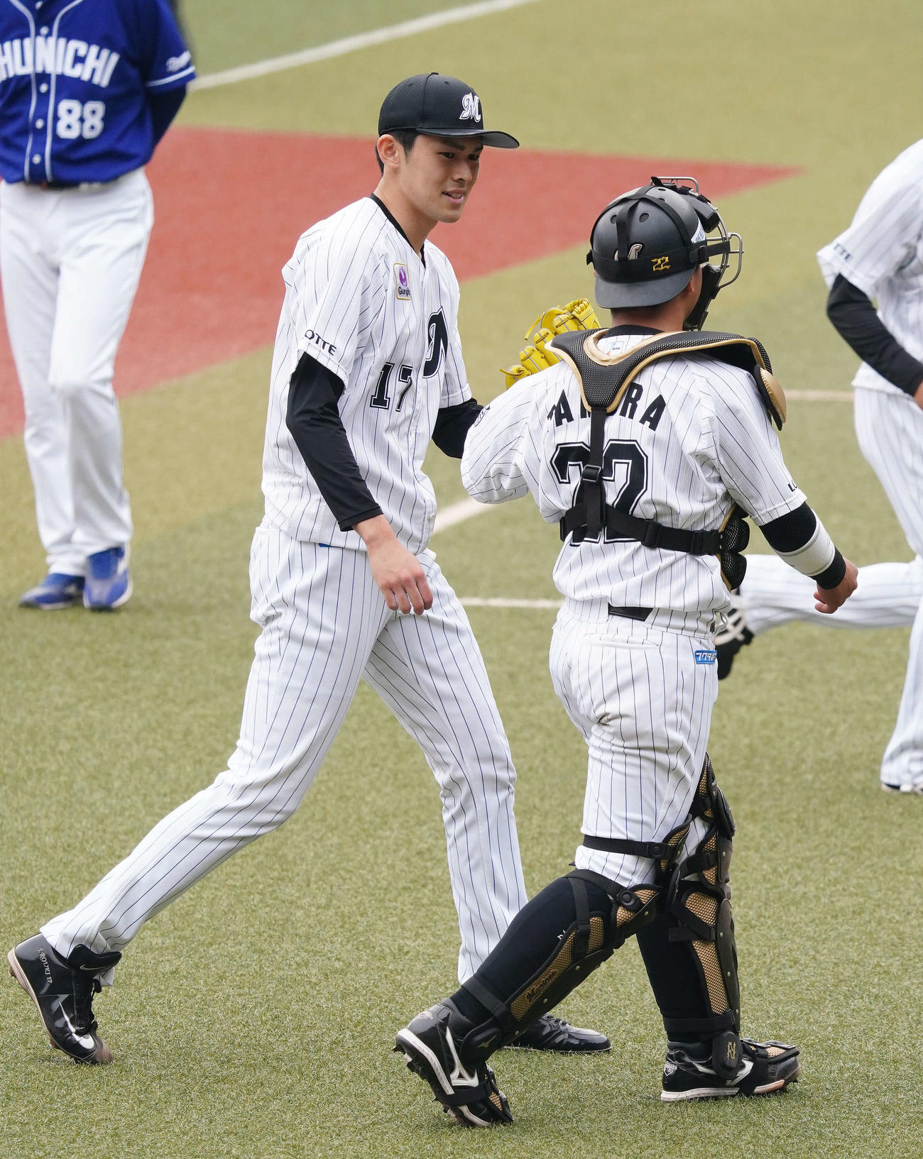 ロッテ対中日　6回表を3者凡退に仕留めたロッテ佐々木朗（左）は田村と笑顔でタッチを交わす
