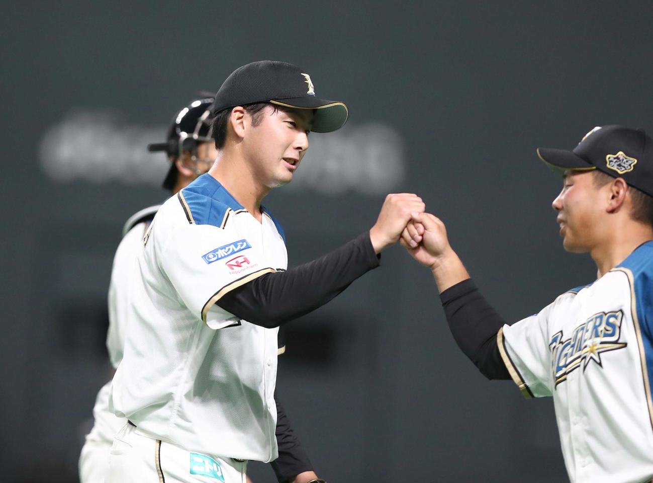 日本ハム対ロッテ　7回に登板し無失点に抑え樋口（右）とタッチする長谷川（撮影・黒川智章）