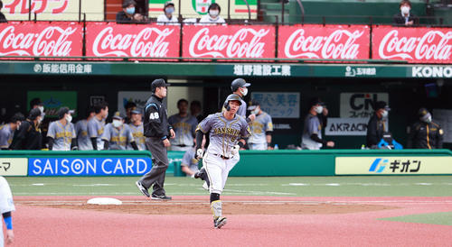 西武対阪神　2回表阪神無死、佐藤輝は右越えソロ本塁打を放ち、ざわつく阪神ベンチを背に一塁を回る（撮影・浅見桂子）